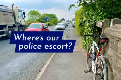 A bike propped up beside a busy road with the caption "Where's our police escort?"